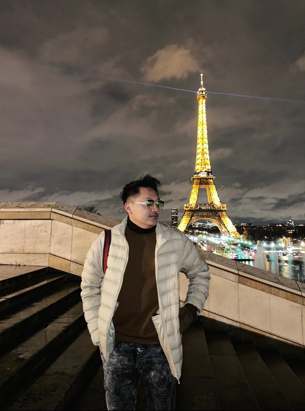 Firman di Trocadéro pada malam hari, dengan Menara Eiffel berkilau keemasan di belakangnya